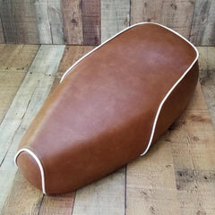Distressed caramel brown Genuine Buddy Kick 125 seat cover with white piping, handmade by Cheeky Seats
